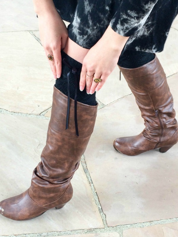 A closeup shot of a girl wearing knee high black socks with bows and brown leather boots.