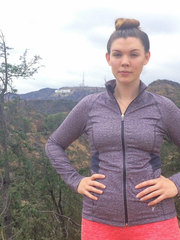 A girl standing on a mountain in workout clothes.