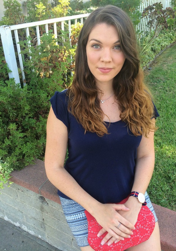 Girl in a blue shirt sitting on a ledge.