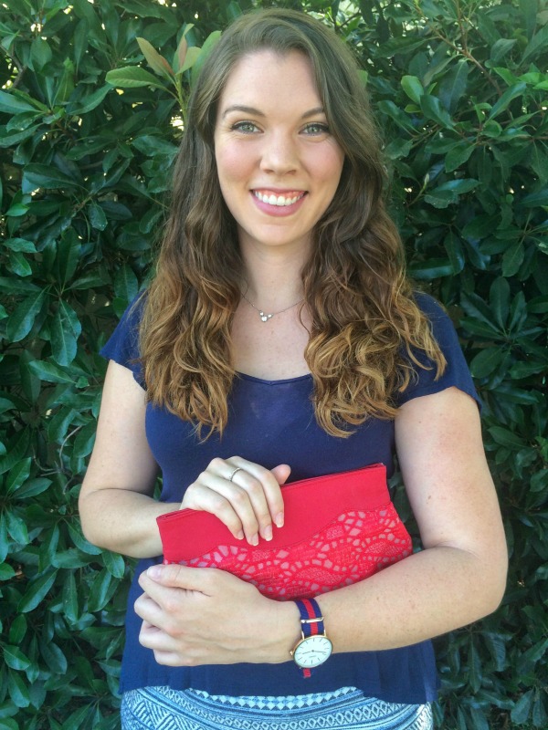 Girl wearing red, white, and blue in front of a hedge.