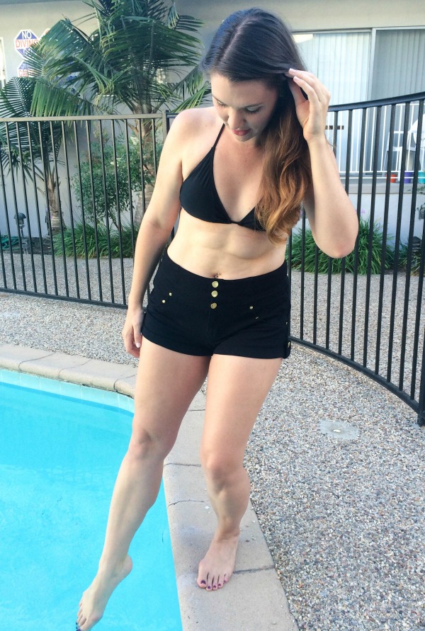 A brunette dipping her toes into a pool.