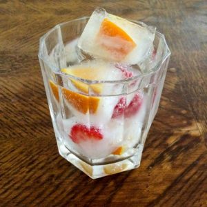 Fruit ice cubes in a glass of sparkling water