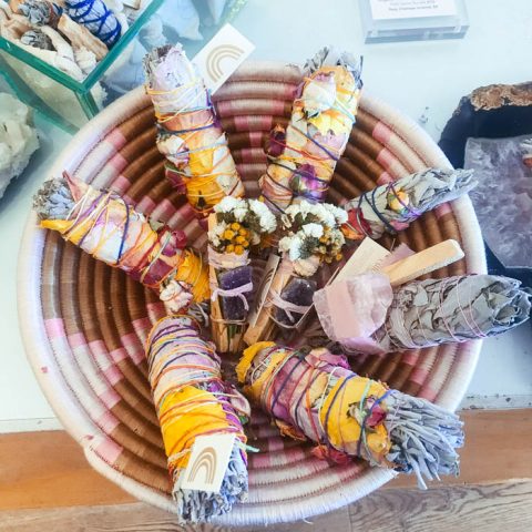 a smudging basket of white sage smudge sticks and palo santo.