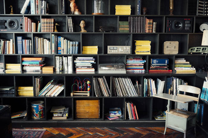 a home library filled with books, records, and decor pieces. A wall filled with bookshelves and books, a home library.