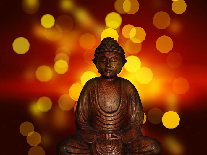 A Buddha meditation statue photographed with lights and bokeh in the background.